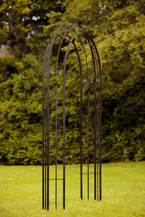 Rosenbogen Cosenza freistehend in einem gepflegten Garten | Pulverbeschichtet Sonderfarbe RAL 8017 Schokobraun Rosenbogen Cosenza freistehend in einem gepflegten Garten | Pulverbeschichtet Sonderfarbe RAL 8017 Schokobraun