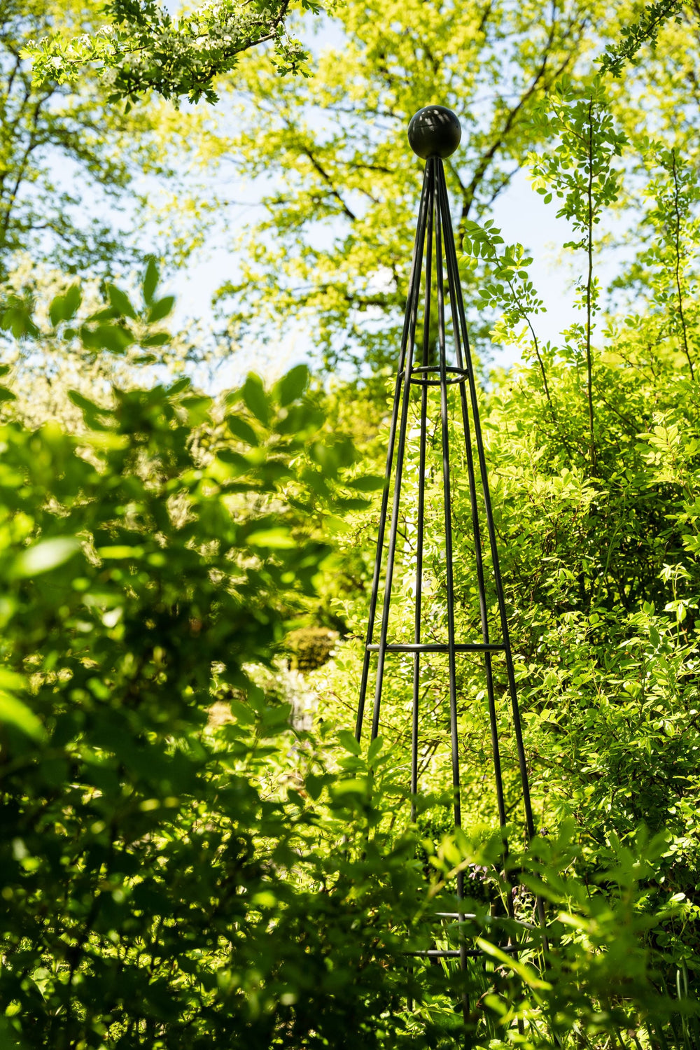 Obelisk Enna im Garten vor grünen Pflanzen, pulverbeschichtet athrazit Obelisk Enna im Garten vor grünen Pflanzen, pulverbeschichtet athrazit