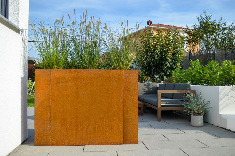 Hochbeet Manarola 40x136x100 in Cortenstahl bepflanzt auf einer Terrasse vor Lounge-Möbeln