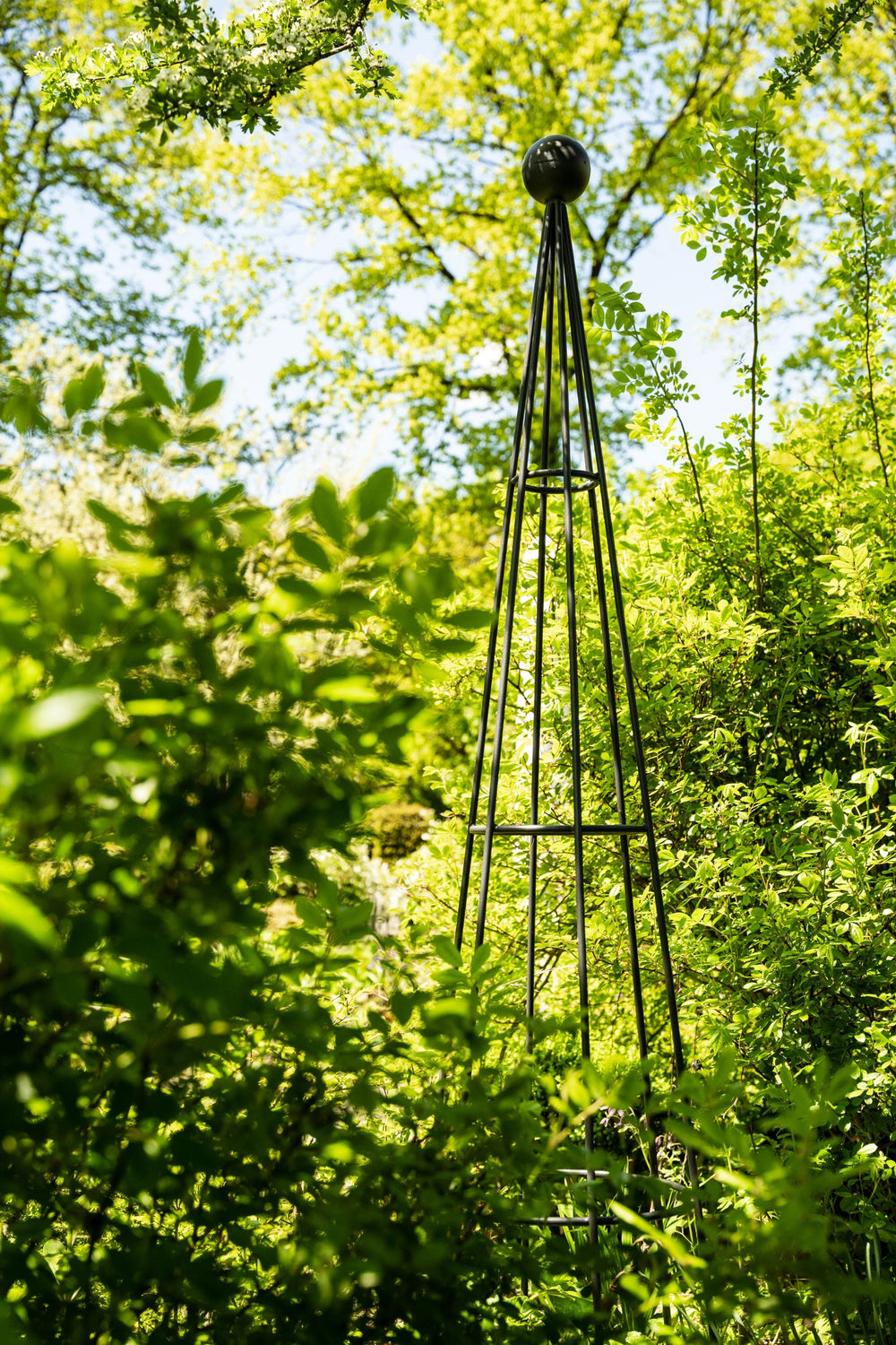 Obelisk Enna im Garten vor grünen Pflanzen, pulverbeschichtet athrazit